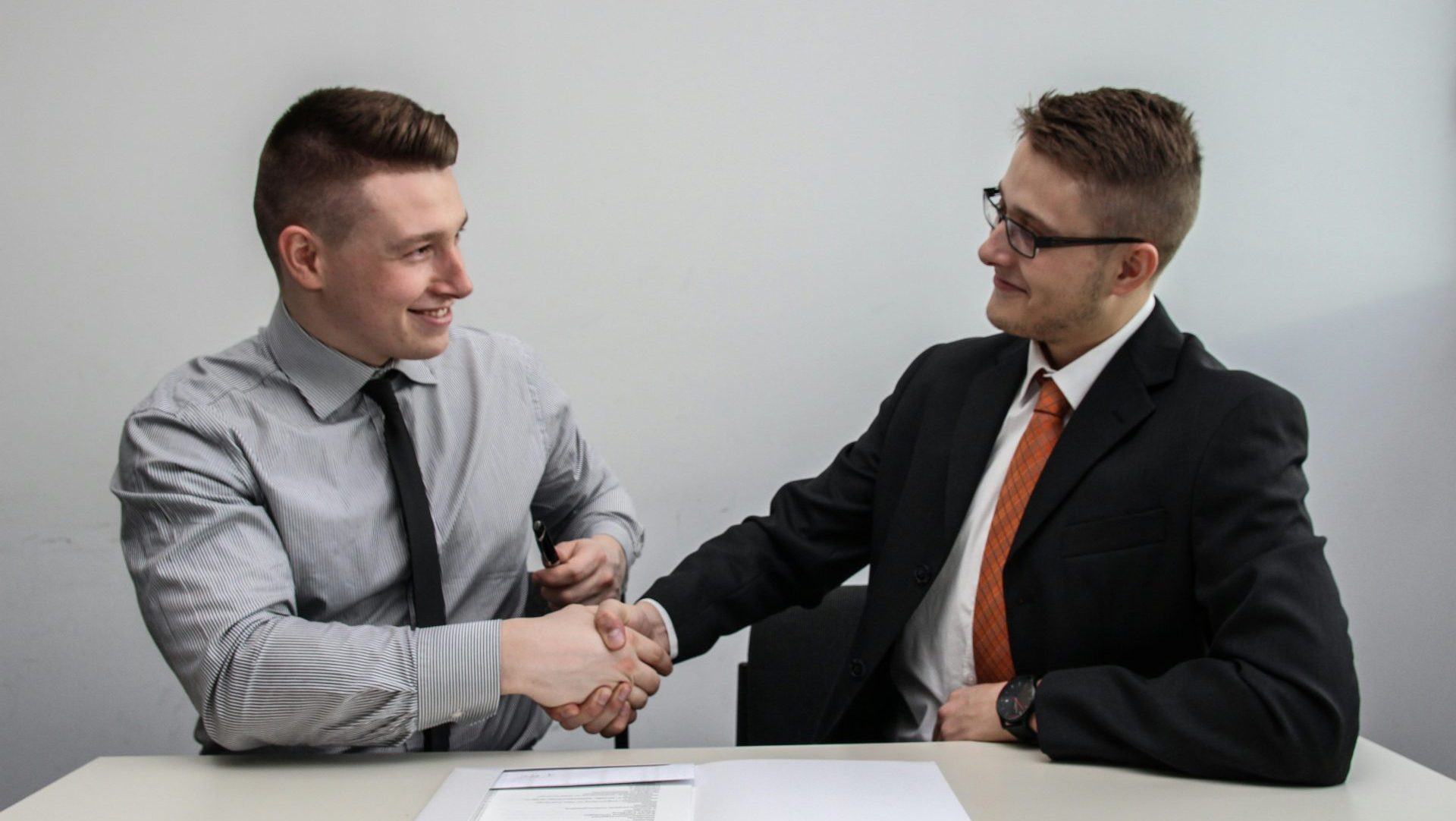 two men facing each other while shake hands and smiling